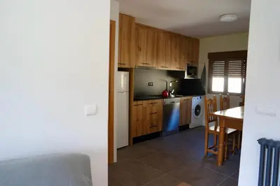 a kitchen with wooden cabinets and a table and a kitchen with a refrigerator at Cainés in Villablino