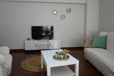 a living room with a white couch and a tv at O Ferrador in Caldas de Reis