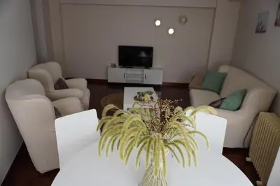 a living room with white couches and a tv at O Ferrador in Caldas de Reis