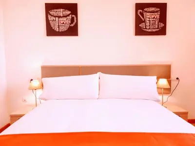 a bedroom with a white bed with two pictures on the wall at Monforte in Monforte de Lemos