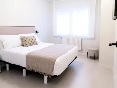 a white bedroom with a bed and a window at Loft América 32 in Melide