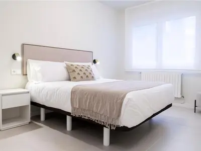 a white bedroom with a large bed and a window at Loft América 32 in Melide