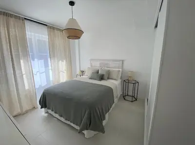 a white bedroom with a bed and a large window at A Terraza in Puentedeume