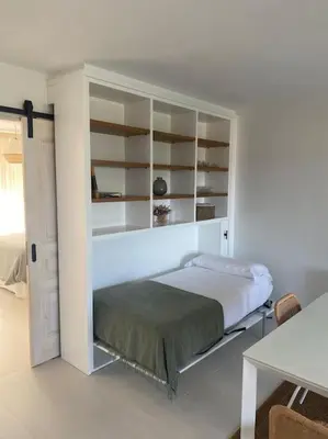 a white bedroom with a bed and shelves at A Terraza in Puentedeume