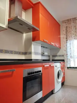 a kitchen with red cabinets and a washing machine at VUT Mencía in Ponferrada