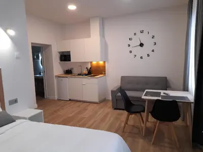 a room with a bed and a table and a clock on the wall at Apartamentos Recunchos in Ourense
