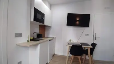 a small white kitchen with a table and chairs at Apartamentos Recunchos in Ourense