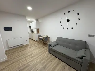 a living room with a couch and a clock on the wall at Apartamentos Recunchos in Ourense