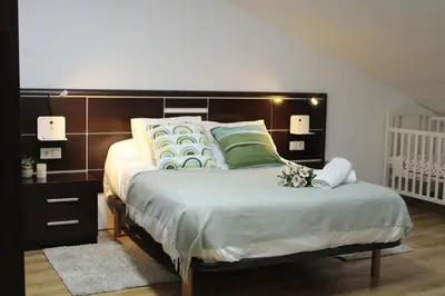 a bedroom with a large bed and a crib at A Ledicia no camiño in Melide