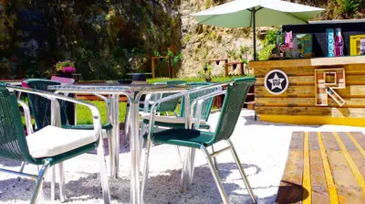 a table with green chairs and an umbrella at Hotel Rock Star in Taboadela