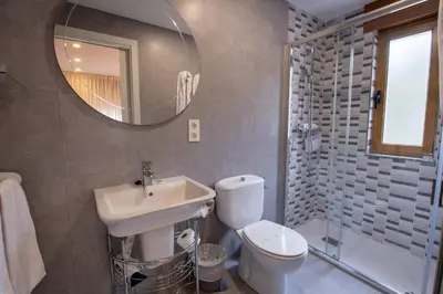 a bathroom with a sink and a toilet and a mirror at Hotel el Pinar in Villapedre