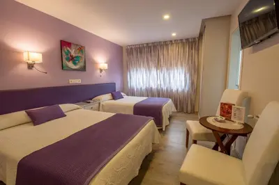a hotel room with two beds and a table at Hotel el Pinar in Villapedre