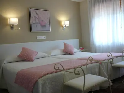 a bedroom with two beds with pink pillows at Hotel el Pinar in Villapedre