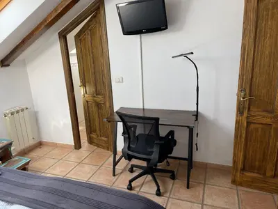 a desk with a chair and a television on a wall at Rural Coliving in Pontevedra