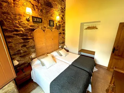 a bedroom with a bed with a stone wall at As Casiñas Bed & Breakfast Porto de Bois in Palas de Rei