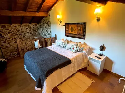 a bedroom with a bed and a stone wall at As Casiñas Bed & Breakfast Porto de Bois in Palas de Rei