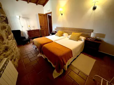a bedroom with a large bed with an orange blanket at As Casiñas Bed & Breakfast Porto de Bois in Palas de Rei