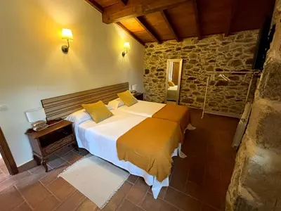 a bedroom with a large bed and a stone wall at As Casiñas Bed & Breakfast Porto de Bois in Palas de Rei
