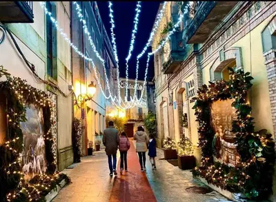 a group of people walking down a street with christmas lights at As Caldas de Mauro in Caldas de Reis