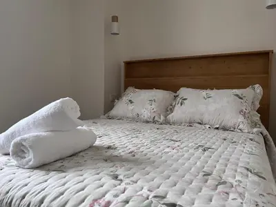 a bed with a white blanket and pillows on it at La Curtía del Neto in El Franco