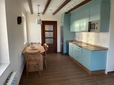 a kitchen with blue cabinets and a table with chairs at La Curtía del Neto in El Franco