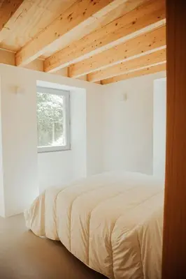 a bed in a white room with a window at Casa de Covés in Puentedeume