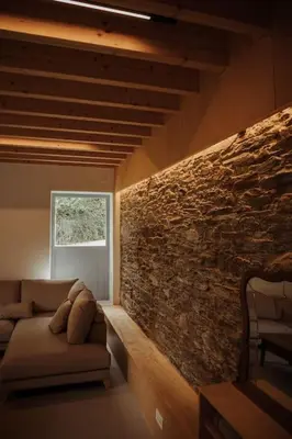 a living room with a couch and a stone wall at Casa de Covés in Puentedeume