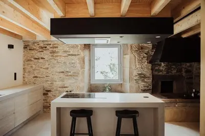 a kitchen with a island with two bar stools at Casa de Covés in Puentedeume