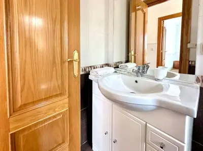a bathroom with a white sink and a wooden door at Carmela House in Melide