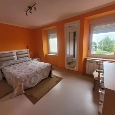 a bedroom with orange walls and a bed and a mirror at Casa Viqueira in Foz