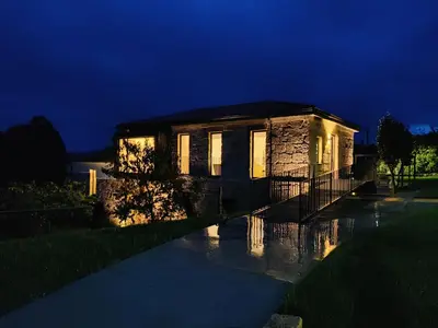 a stone house with lights on in the night at Casa Velasca in Mesiego