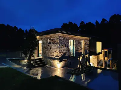 a stone house at night with its lights on at Casa Velasca in Mesiego