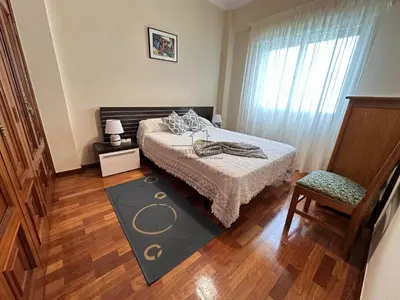 a bedroom with a bed and a chair and a window at Balcón da Habana in Ourense