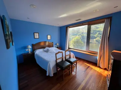 a blue bedroom with a bed and a large window at Casa Río Miño CORTEGADA in Cortegada