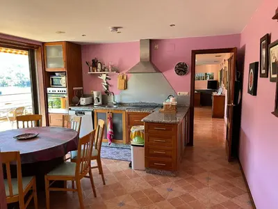 a kitchen with pink walls and a table and a table and chairs at Casa Río Miño CORTEGADA in Cortegada