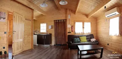 a living room with a leather couch in a log cabin at Cabañas Madarsu in Vigo de Sanabria
