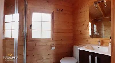 a bathroom with a toilet and a sink and a window at Cabañas Madarsu in Vigo de Sanabria
