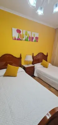 two beds in a bedroom with yellow walls at Piso Ainoa Playa de Covas in Viveiro