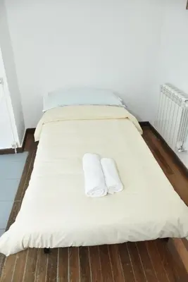 a white bed with two white towels on it at O lar Albergue Larouco in Laroco