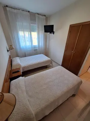 a small room with two beds and a tv at Hotel Berna in La Rúa