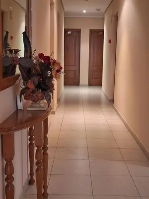a hallway with a table with a vase of flowers on it at Hotel Berna in La Rúa