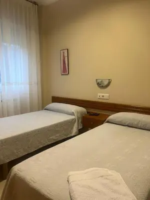 a hotel room with two beds and a window at Hotel Berna in La Rúa