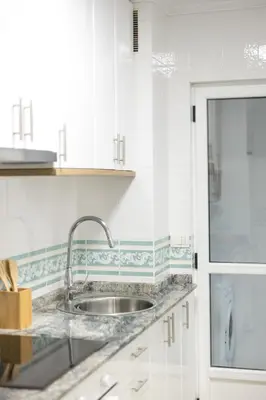 a kitchen with a sink and white cabinets at Apartamento Ronda Muralla in Lugo