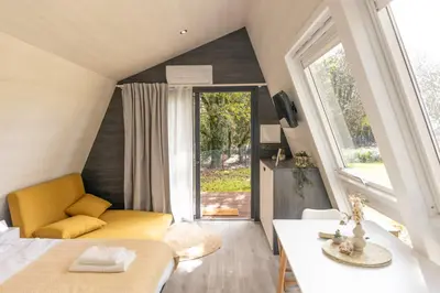 a room with a bed and a couch and a window at EcoCamp San Román by SuitesNature in Lugo