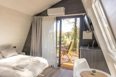 a bedroom with a bed and a balcony with a chair at EcoCamp San Román by SuitesNature in Lugo