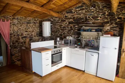 a kitchen with white appliances and a stone wall at Cabo Do Mundo Casa Rural in Chantada