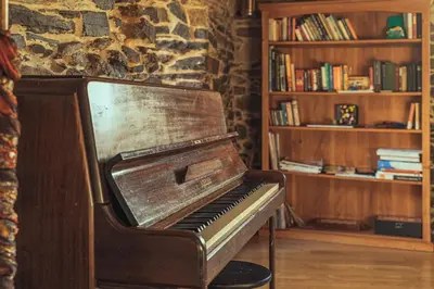 an old piano sitting in a room next to a book shelf at Cabo Do Mundo Casa Rural in Chantada