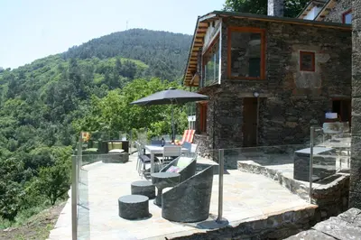 a house with a table and an umbrella on a patio at Cabo Do Mundo Casa Rural in Chantada