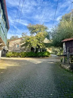 an empty street with a stone building and trees at Casa Redonda in Ourense