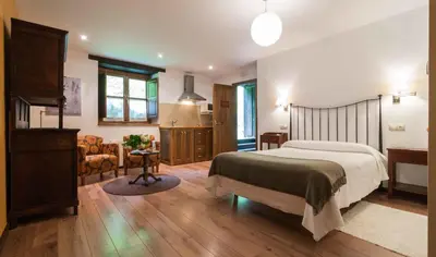 a bedroom with a bed and a living room at Apartamentos Rurales Sierra in Palacio de Naviego